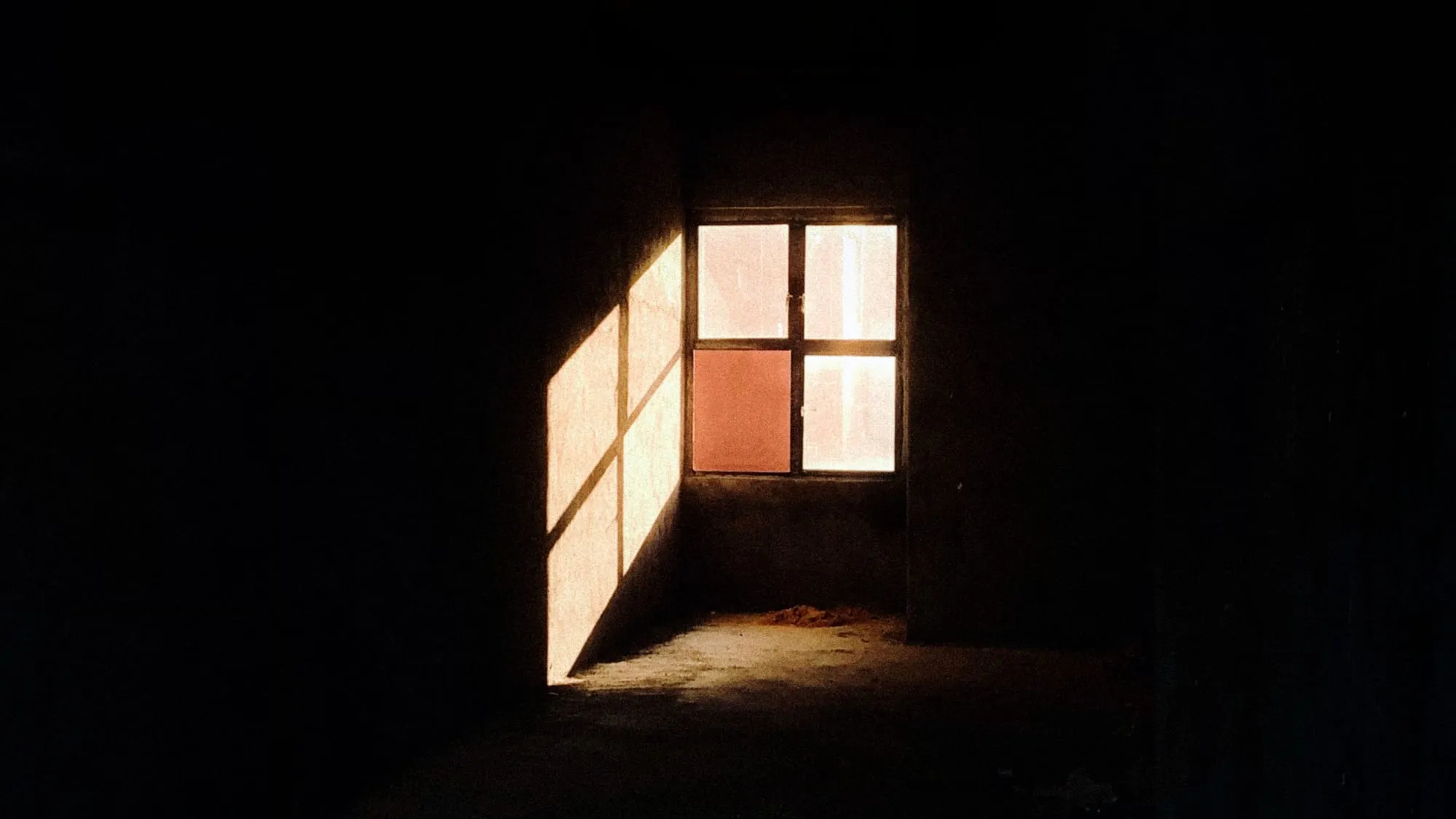 Sonnenlicht fällt durch ein kleines Fenster in einen dunklen Raum
